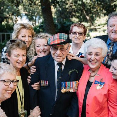 A veteran wearing service medals with family and friends at a commemoration